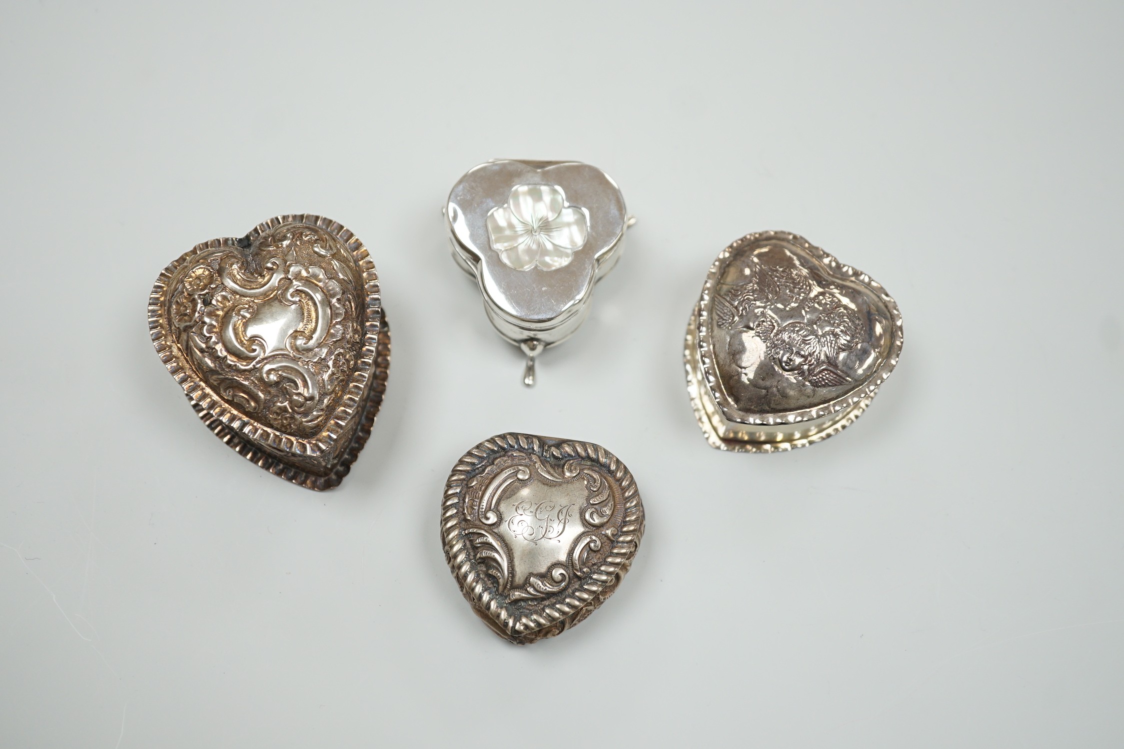 Three Victorian/Edwardian repousse silver heart shaped trinket boxes, largest 56mm and a similar mother of pearl inlaid 'pansy' trinket box, by Saunders & Shepherd, gross weight 1106 grams.